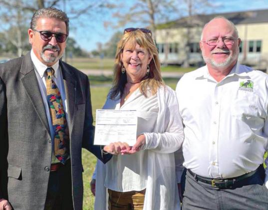 From left, Woodlands Conservancy Founding Board Members, Councilman Benny Rousselle and Executive Director Katie Brasted, stand alongside Lee Dupont, Land Chair and Vice President of Woodlands Conservancy. The group is showing a check for $3.25 million that funded the land acquisition – a result of over two decades of work to preserve the 649-acre forested wetland.