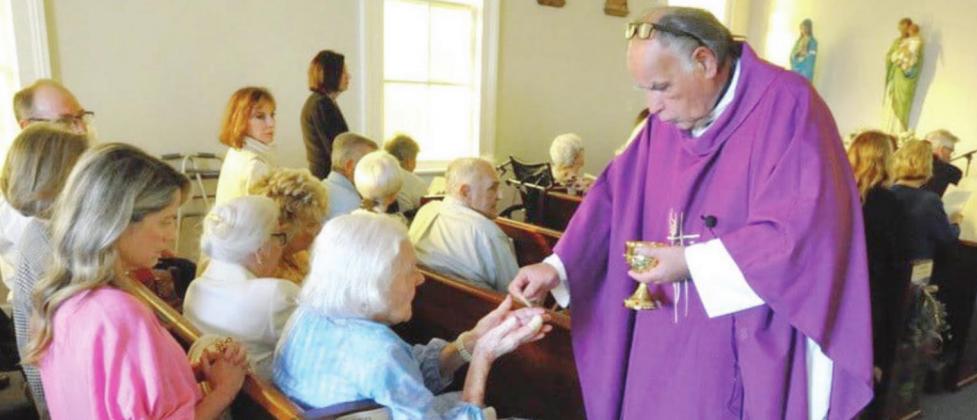 Fr. Gerry Stapleton, Pastor of St. Patrick’s Church in Port Sulphur who oversees St. Ann Church in Empire, gives communion to local Eva Vujnovich during the special mass celebrating St. Ann’s 100th anniversary on Saturday, March 5.