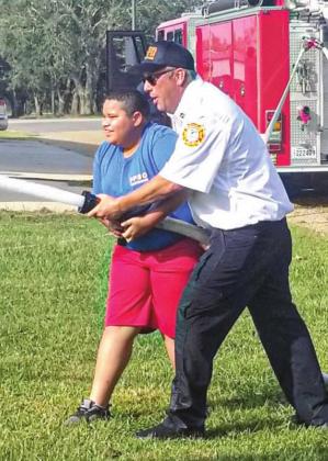 Plaquemines Parish Fire Dept. Captain Kevin Coleman shows a Young Marine how to work the fire hose at the Young Marine weekend drill held on Oct. 23.