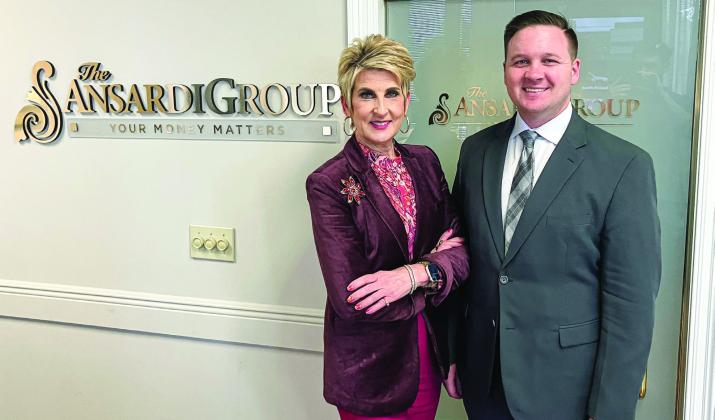 Danica Ansardi (left) and Tray Ansardi (right) pose for a photo beside The Ansardi Group company logo at their Belle Chasse office.