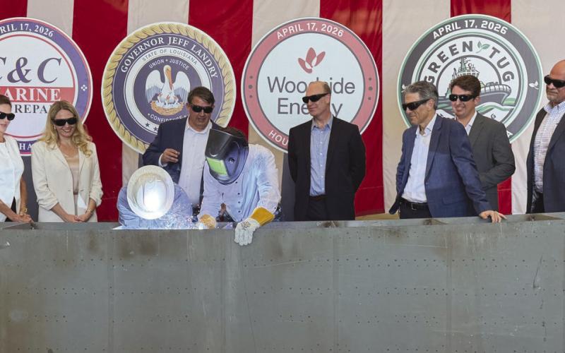 Governor Je Landry, center, with a welding shield, performed a ceremonial weld commemorating the start of the construction of 4 tugs being built at C &amp;amp; C Marine in Belle Chasse as o cials from the state, C &amp;amp; C, Woodside Energy, and Green Tug Towing look on. The tugs will be operated by Green Tug Towing and used to maneuver LNG Ships at Woodside's Calcasieu Pass LNG facility under construction near Lake Charles.
