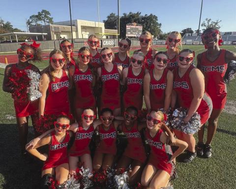 The cheer team on the sidelines getting ready to cheer on the bulldog football team.