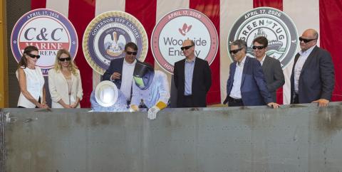 Governor Je Landry, center, with a welding shield, performed a ceremonial weld commemorating the start of the construction of 4 tugs being built at C &amp; C Marine in Belle Chasse as o cials from the state, C &amp; C, Woodside Energy, and Green Tug Towing look on. The tugs will be operated by Green Tug Towing and used to maneuver LNG Ships at Woodside's Calcasieu Pass LNG facility under construction near Lake Charles.