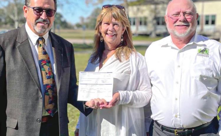 From left, Woodlands Conservancy Founding Board Members, Councilman Benny Rousselle and Executive Director Katie Brasted, stand alongside Lee Dupont, Land Chair and Vice President of Woodlands Conservancy. The group is showing a check for $3.25 million that funded the land acquisition – a result of over two decades of work to preserve the 649-acre forested wetland.