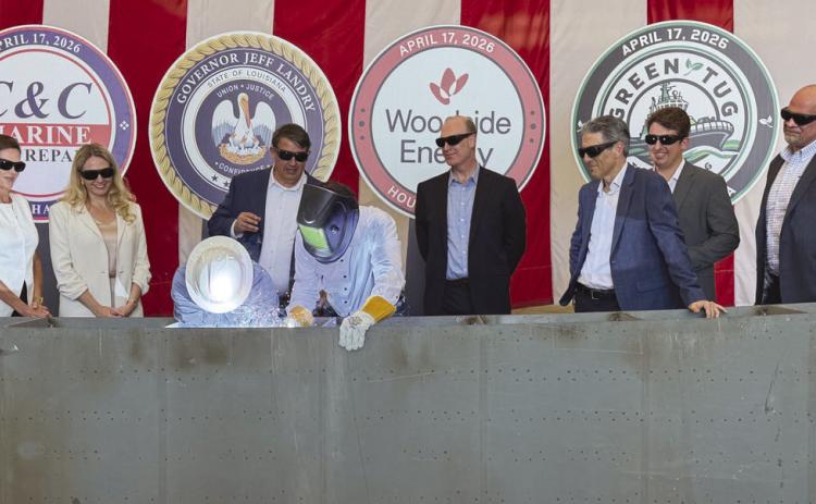 Governor Je Landry, center, with a welding shield, performed a ceremonial weld commemorating the start of the construction of 4 tugs being built at C &amp; C Marine in Belle Chasse as o cials from the state, C &amp; C, Woodside Energy, and Green Tug Towing look on. The tugs will be operated by Green Tug Towing and used to maneuver LNG Ships at Woodside's Calcasieu Pass LNG facility under construction near Lake Charles.