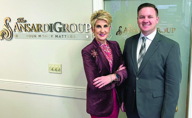Danica Ansardi (left) and Tray Ansardi (right) pose for a photo beside The Ansardi Group company logo at their Belle Chasse office.