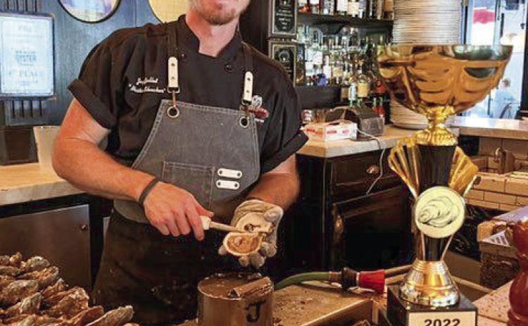 Jordan Gallet, Master Shucker at Superior Seafood & Oyster Bar, poses for a photo on November 4 with his National Oyster Shucking Champion trophy.